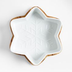 a white bowl with an intricate design on the bottom and wooden rim, sitting in front of a white wall