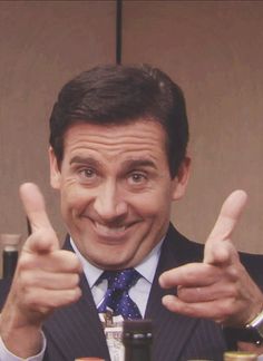 a man in a suit and tie giving the thumbs up while sitting at a table