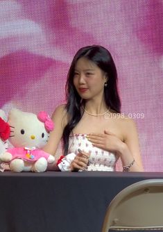 a woman in a white dress holding a hello kitty stuffed animal