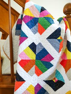 a multicolored quilt sitting on top of a wooden chair