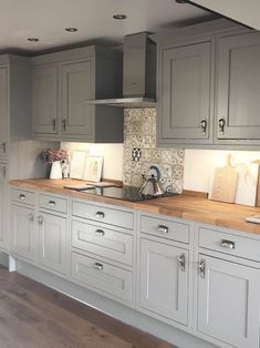 a kitchen with gray cabinets and wooden counter tops