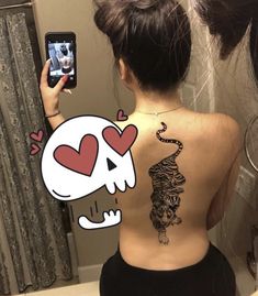 a woman with a tattoo on her back taking a selfie