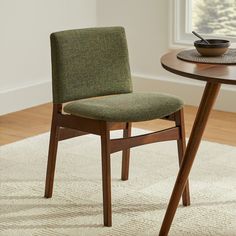 a wooden table with a bowl on top of it next to a chair and rug