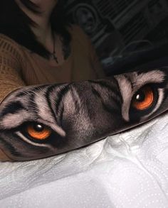 an animal with orange eyes laying on top of a bed