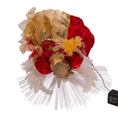 a red and white flower with gold sequins on it next to a battery