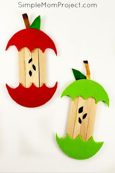 two apples made out of popsicle sticks with faces on them, one is green and the other is red