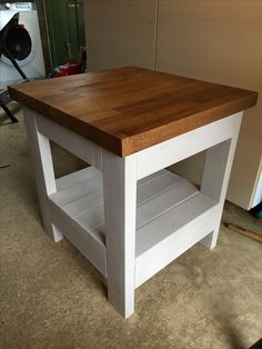 a kitchen island made out of two different pieces of wood and painted white with shelves on each side