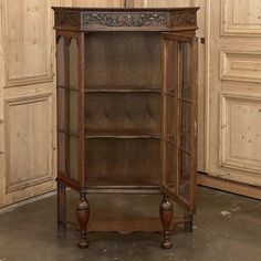 an old wooden bookcase with carvings on the top and bottom, in front of a paneled wall