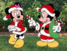 two cartoon characters dressed as santa and person holding candy canes in front of some trees