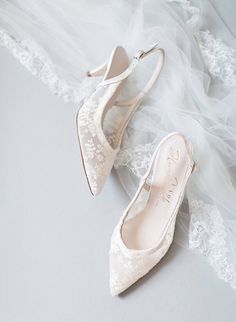 a pair of wedding shoes with lace on the bottom and heels in the middle, sitting on a white surface