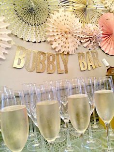 there are many wine glasses lined up on the table with paper fans in the background