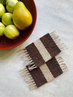 a bowl of fruit next to a woven table runner