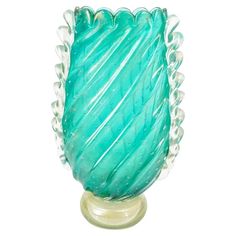 a green glass vase sitting on top of a wooden stand with beads around the base