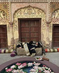 a woman is laying on a couch in front of a building with flowers growing out of it