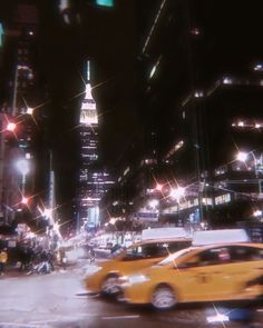 a yellow taxi cab driving down a street next to tall buildings in the city at night