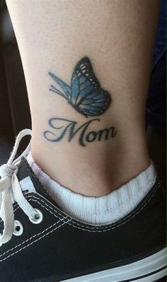 a woman's foot with a butterfly tattoo on her left ankle and the word mom written in cursive font