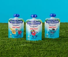 three bottles of stonyfield organic yogurt sitting in the grass