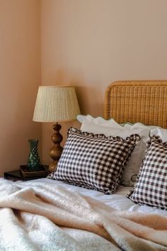 a bed with two pillows on top of it next to a night stand and lamp