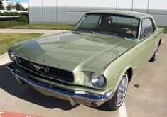 an old green car parked in a parking lot