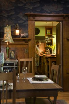 a woman standing in the doorway of a kitchen next to a dining room table and chairs