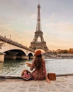 a woman sitting on the ground in front of the eiffel tower