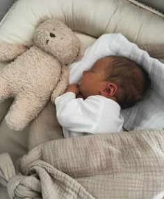 a baby sleeping in a crib next to a teddy bear