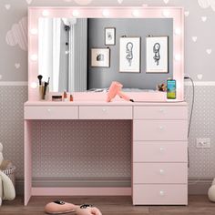 there is a pink vanity with lights on the mirror and stuffed animals in front of it