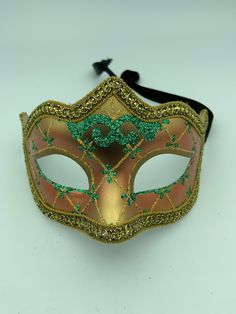 "This is a very nice original handmade and hand painted Venezia masquerade face mask made in Italy. The design on the shiny gold and orange face mask features turquoise blue and multi-color glitter with a border of gold lace and gold rope around the edges. It comes with a black ribbon tie and is stamped on the back \"Original Hand Painted Made in Italy Venezia\". The mask measures approximately 6 5/8\" long and 3 3/4\" wide and is in very good preowned condition with light wear on the back of th Hand Painted Masks For Masquerade Carnival, Hand Painted Masks For Carnival Masquerade, Hand Painted Masks And Prosthetics For Carnival, Artistic Red Masquerade Mask For Mardi Gras, Multicolor Masquerade Mask For Carnival Festivals, Hand Painted Carnival Masks, Multicolor Masquerade Mask For Carnival, Multicolor Eye Masquerade Mask For Carnival, Venetian Masks For Mardi Gras Carnival