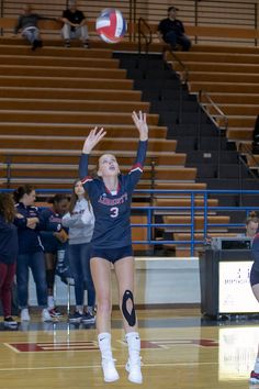 a female volleyball player jumping up to hit the ball