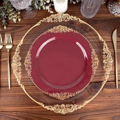 a red plate with gold trim sits on a wooden table next to utensils