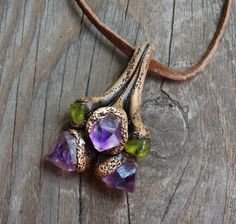 a necklace with amethysts and other stones on it sitting on a wooden surface