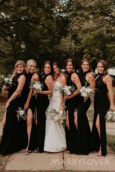 a group of women standing next to each other wearing black dresses and holding bouquets