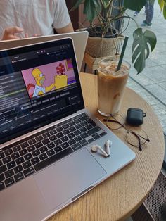 an open laptop computer sitting on top of a wooden table next to a cup of coffee