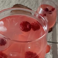 two glasses filled with pink liquid and raspberries