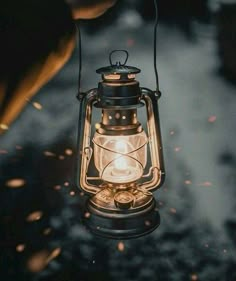 an old fashioned lantern is lit up in the dark, with sparks coming from it