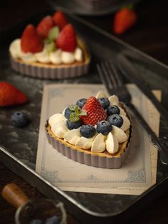 two desserts with strawberries, bananas and blueberries on top are sitting on a tray