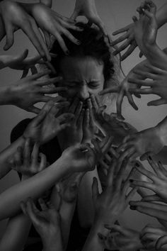 a woman surrounded by many hands reaching up to her face