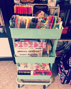 a green cart filled with lots of different colored pens and pencils on top of it