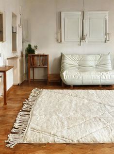 a white couch sitting on top of a hard wood floor next to a wooden table