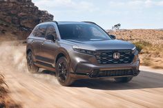 a grey honda passport driving down a dirt road