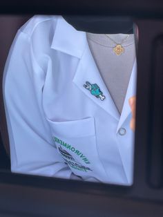 a close up of a person's white coat and necklace in the back of a car