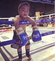 a young child wearing boxing gloves standing in the ring