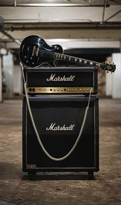 an electric guitar and amp sitting on top of each other in a parking garage area