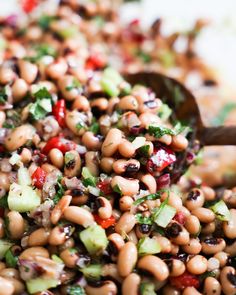 a salad with beans, cucumbers, and other vegetables in a wooden spoon