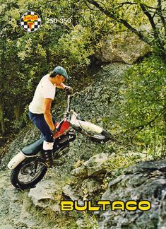 a man riding on the back of a dirt bike down a rocky hill next to trees