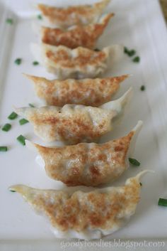 four dumplings on a white plate with green garnish