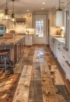 a large kitchen with wooden floors and white cabinets, along with an island in the middle