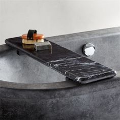 a black marble bathtub with a brush and soap on the edge next to it