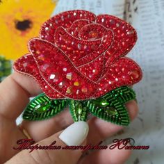 a red rose brooch with green leaves on it