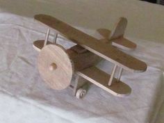 a wooden toy airplane sitting on top of a white sheet